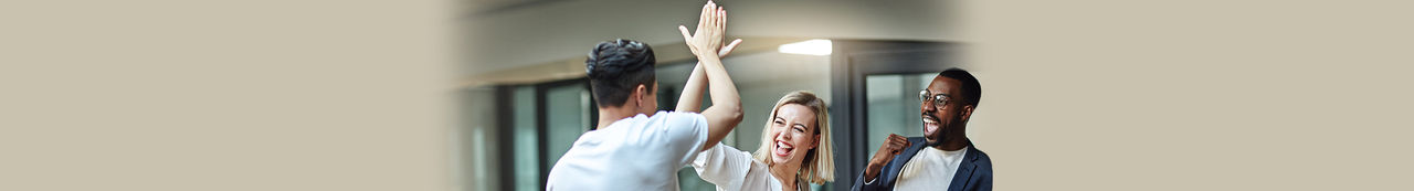 Two people celebrating with a high five while a third person looks on