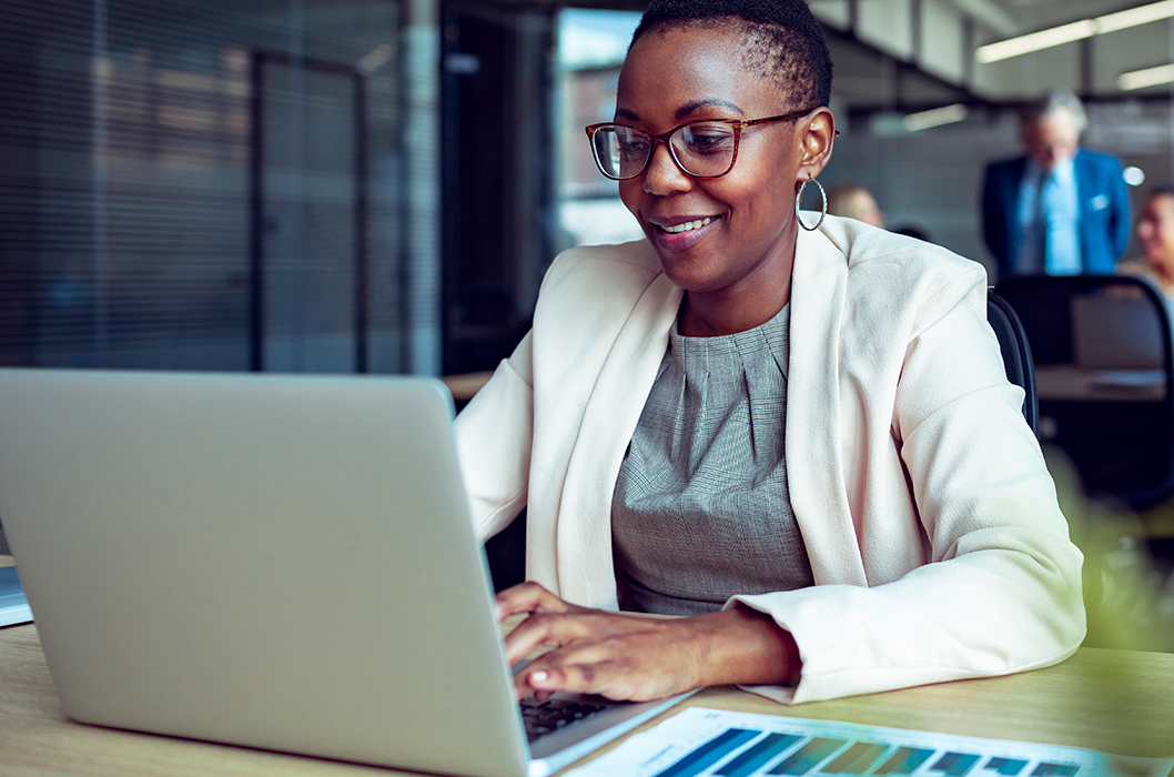 Woman with glasses in business attire using a laptop